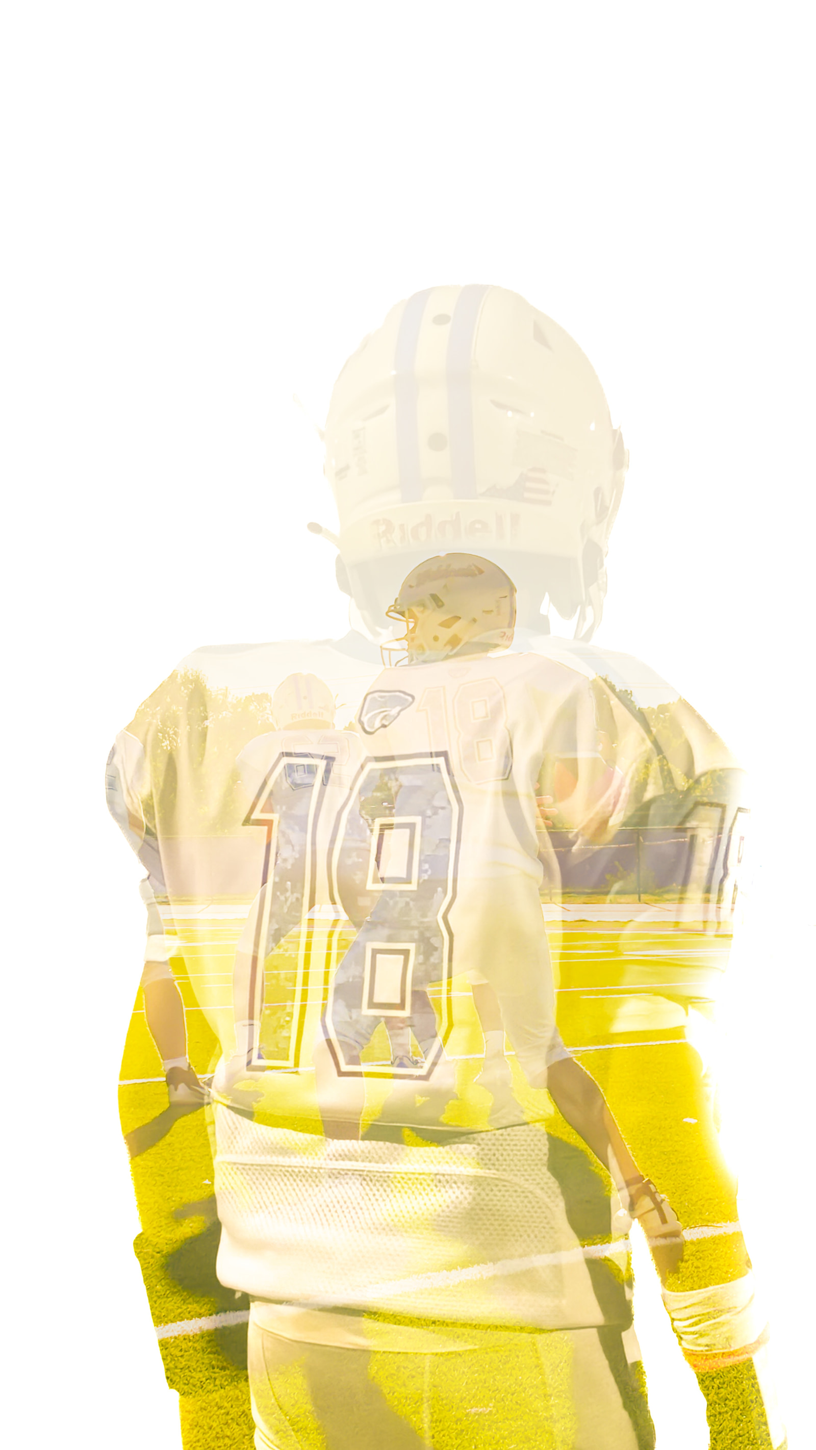 A football player in a white jersey with the number 18 stands on a field, viewed from behind.
