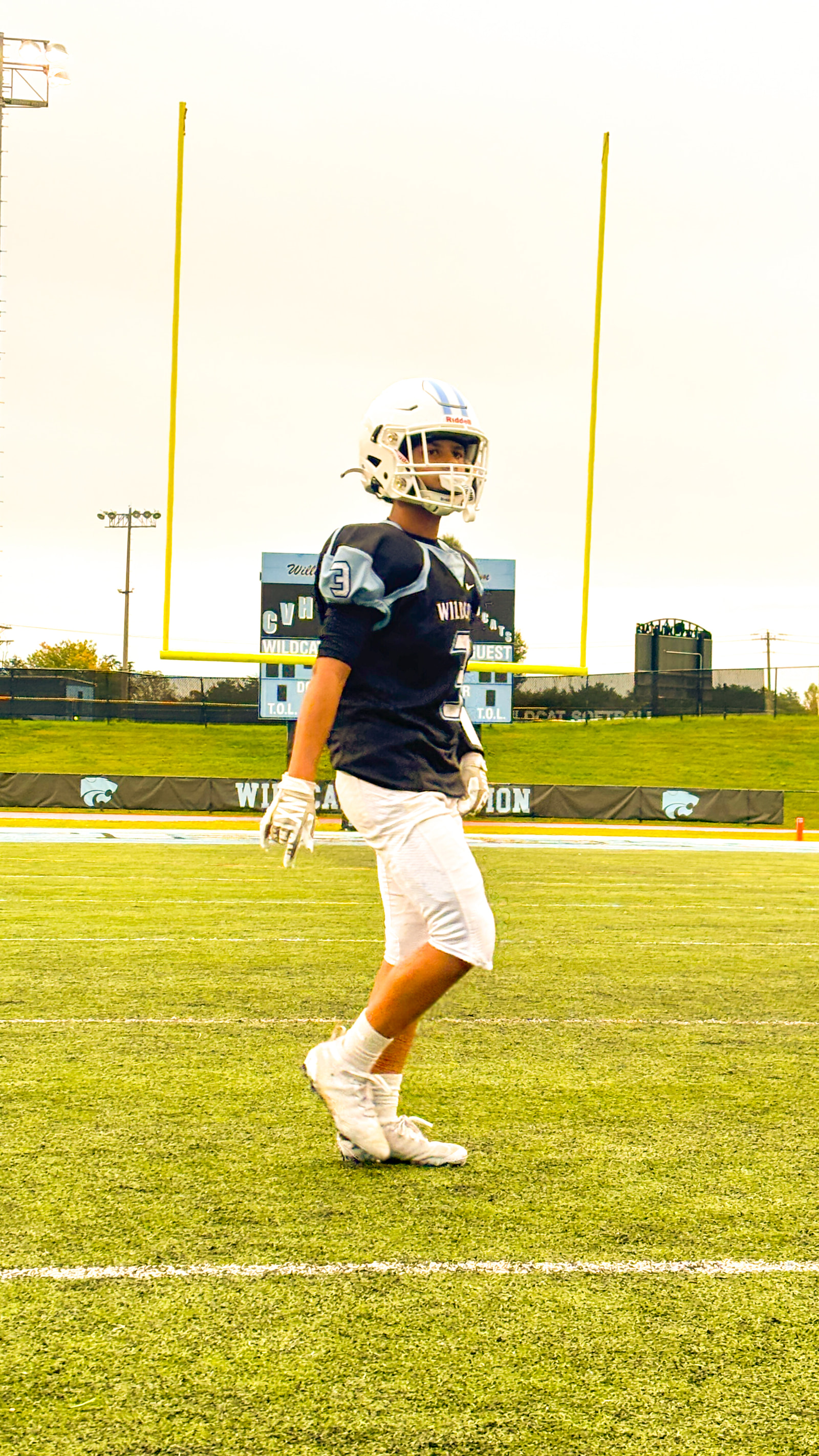 A football player stands on a field near the goalposts.